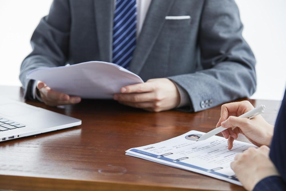 Hiring manager reviewing a candidate CV across a desk — how MOM assesses a Singapore Employment Pass application